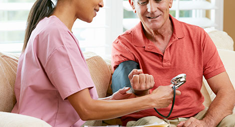 An older gentleman receiving a blood test from a female healthcare professional at home